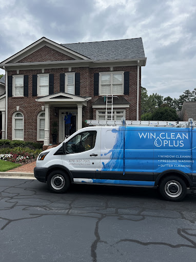 Win Clean Plus team providing exterior residential window cleaning with branded service vehicle outside a home.